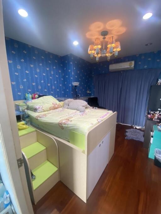 Well-lit bedroom with a loft bed and vibrant blue wallpaper