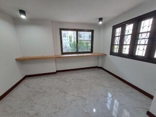 Spacious bedroom with large windows and a wooden desk