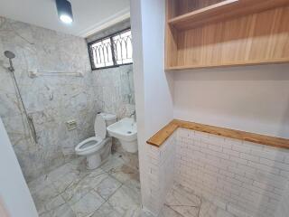 Bathroom with marble tiles, toilet, sink, and shower