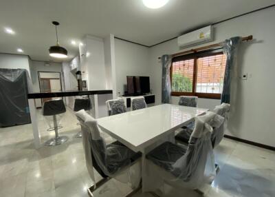 Modern dining area with white table and black chairs, adjacent to kitchen