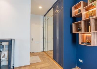 Modern hallway with wooden floor, mirrored closet and wall shelves