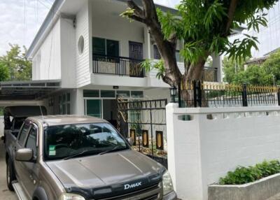 Suburban two-story house with a tree and parked vehicle