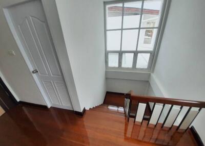 Staircase with wooden floors and large window