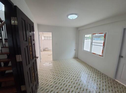 Interior view of a room with tiled floor, window, and stairs