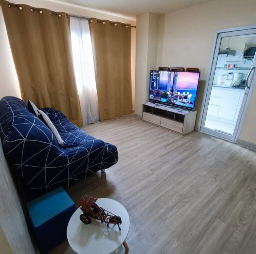 Cozy living room with a television, couch, and a window with curtains