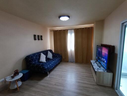 Living room with sofa, television, and curtains