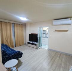 Living room with sofa, TV, and wooden flooring