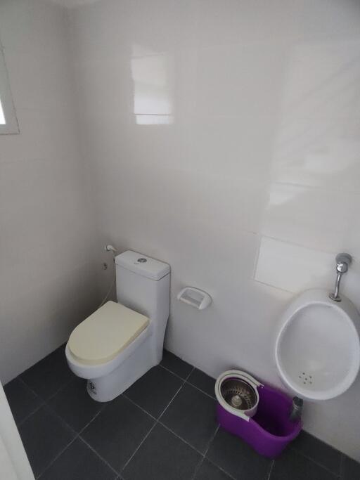 Bathroom with toilet, urinal, and cleaning supplies