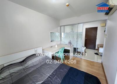 A well-lit bedroom with a bed, desk, chair, and mirrored closet doors