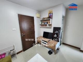 A cozy living room with a wooden door, a white shelf, and a small entertainment center