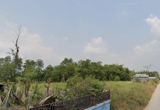 Vacant plot of land with some trees and a small structure visible in the background