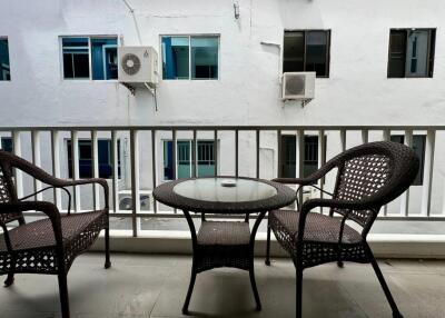 balcony with wicker furniture overlooking neighboring building