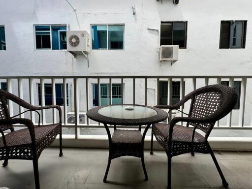 balcony with wicker furniture overlooking neighboring building