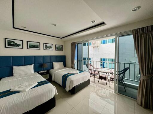 Bedroom with two single beds, balcony view, and modern decor