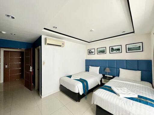 Modern bedroom with two beds, blue headboards, and wall art