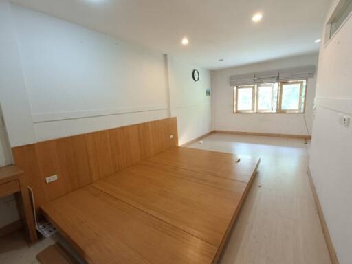 Spacious bedroom with wooden paneling and three windows