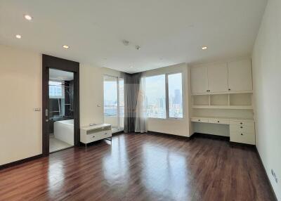 Spacious living room with hardwood floors and large windows with city view.