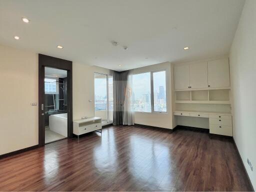 Spacious living room with hardwood floors and large windows with city view.