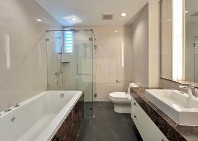 Modern bathroom with a glass-enclosed shower, bathtub, and double sink vanity