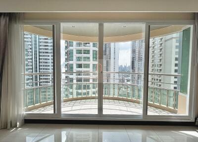 Spacious living room with large glass doors and balcony offering city skyline views