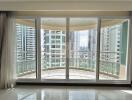 Spacious living room with large glass doors and balcony offering city skyline views