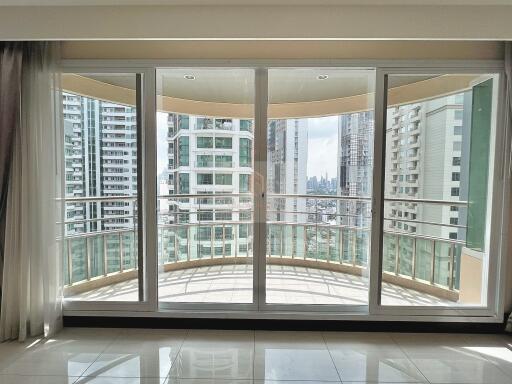 Spacious living room with large glass doors and balcony offering city skyline views