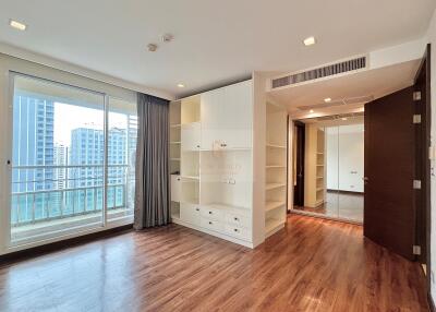 Modern living space with hardwood floors, built-in shelves, and large windows.