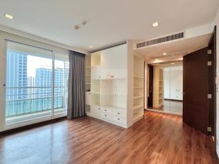 Modern living space with hardwood floors, built-in shelves, and large windows.