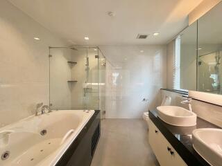 Modern bathroom with jacuzzi, glass shower, double sinks, and large mirror