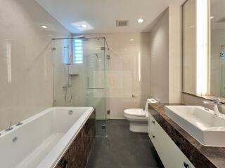 Modern bathroom with glass-enclosed shower, bathtub, and dual sinks