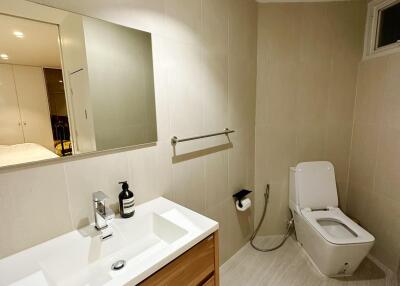 Modern bathroom with sink, mirror, toilet, and towel rack