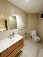 Modern bathroom with sink, mirror, toilet, and towel rack