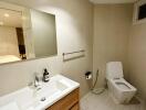 Modern bathroom with sink, mirror, toilet, and towel rack