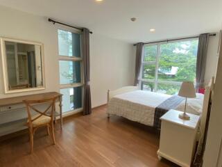 Well-lit bedroom with large windows, a bed, and a dresser