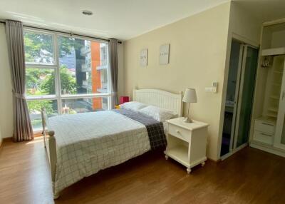 Bedroom with large window view, bed, nightstand, and adjacent bathroom