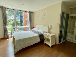 Bedroom with large window view, bed, nightstand, and adjacent bathroom