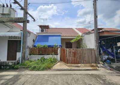 Single-story house with a fenced front yard and a blue canopy