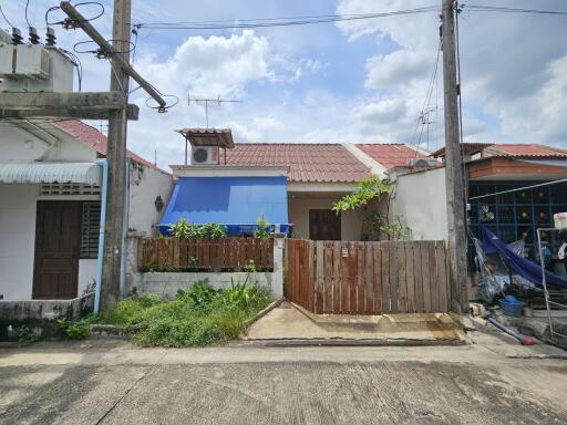 Single-story house with a fenced front yard and a blue canopy