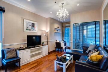 A well-lit modern living room with a chandelier, TV, and seating area