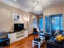 A well-lit modern living room with a chandelier, TV, and seating area