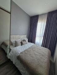 Modern bedroom with a comfortable bed, soft furnishings, and a large window with curtains