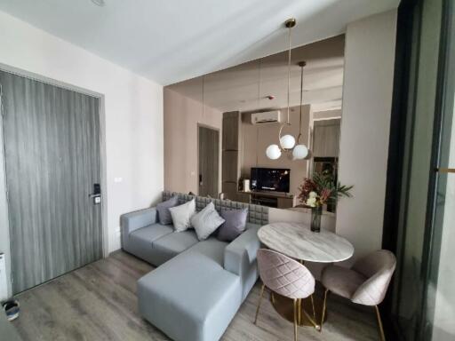 Modern living room with gray sectional sofa, round dining table with chairs, large mirror, and wall-mounted TV
