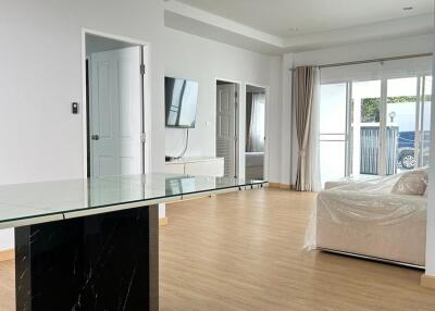 Modern living room with glass table, wall-mounted TV, and large sliding doors to patio