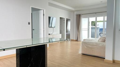 Modern living room with glass table, wall-mounted TV, and large sliding doors to patio