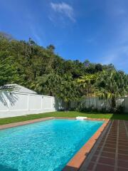 Swimming pool with surrounding greenery under a blue sky