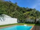 Swimming pool with surrounding greenery under a blue sky