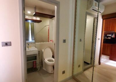 Small bathroom with toilet, sink, and a mirrored closet in the hallway outside