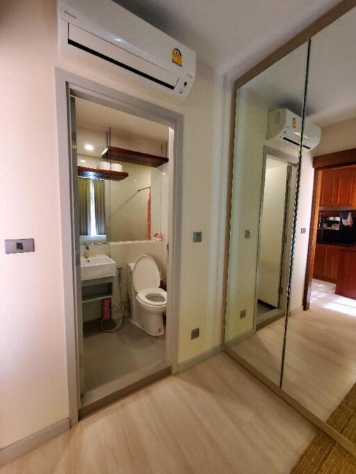 Small bathroom with toilet, sink, and a mirrored closet in the hallway outside
