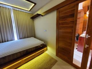 A modern bedroom with a bed, wooden door, and side office
