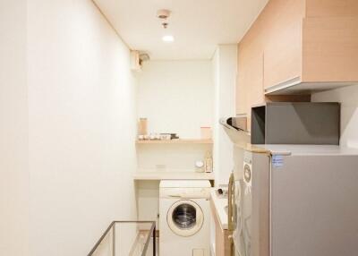 Compact laundry room with washing machine, refrigerator, and storage shelves